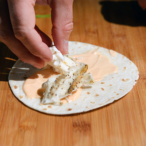  Next, place some fish on the tortilla shells, over top of that spicy, creamy goodness