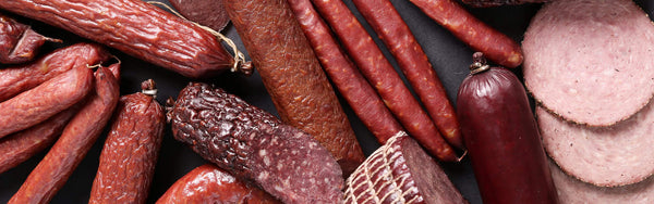 close up image of a spread of read meats including sausages