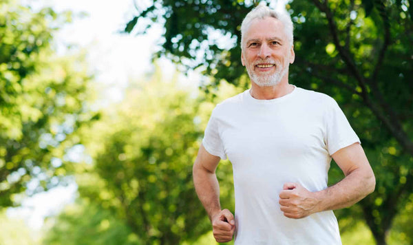 image of a healthy older man running outside, green woods in the background