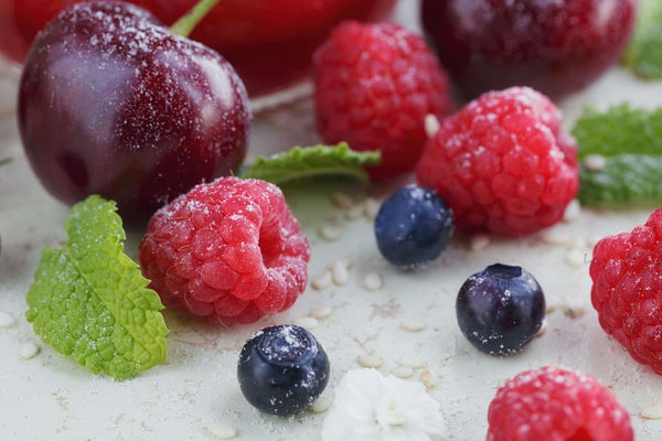 Raspberry, sweet cherry and bilberry on white wooden background. Close up.