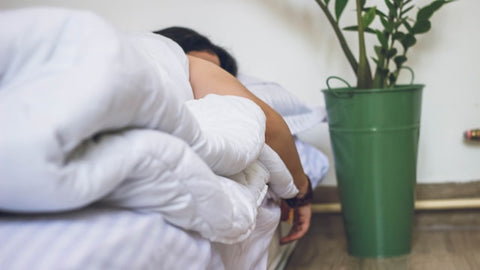 Ein Bett mit einer schlafenden Person darin - Stress vermeiden bei Bindegewebsschwäche