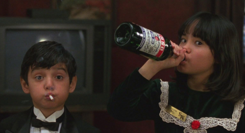 Movie Still from the film "4 Rooms" of two children, one with a bottle of champagne and the other with a cigarette in their mouth.