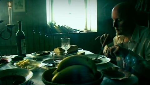 Film still from the 2006 film Cannibal showing a man eating at a dinner table.