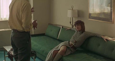 Jane Fonda sitting on a green couch with a man standing in front of her, film still from the movie Klute