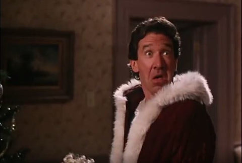 Scott Calvin in The Santa Clause holding a shocked expression while wearing a santa outfit.