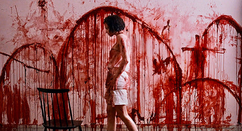 Film still from the horror movie Trouble Every Day, showing actress Beatrice Dalle in a room covered with blood.