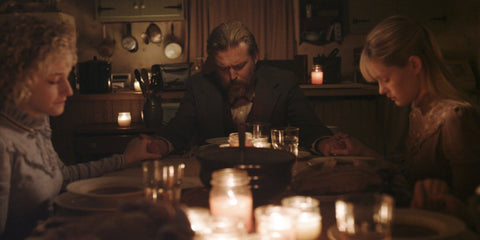 Film still from the cult horror film We are what we are showing the family sitting down for a meal at their dinner table.