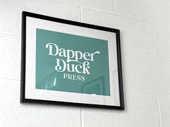 photo of the Dapper Duck Press logo framed on a wall