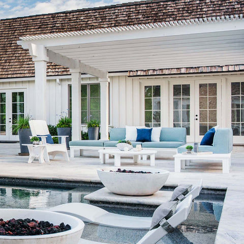 Outdoor sectional and Adirondack with blue cushions and pillows by a pool with Ledge in-pool chaise loungers