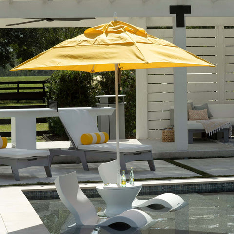 In-pool chairs and side tables covered from the sun by an in-pool umbrella.