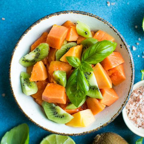 Bowl with cantaloupe, kiwi, mint and other fruit salad ingredients