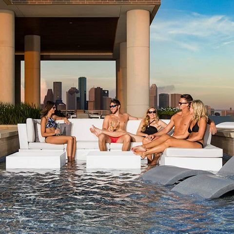 Group of people sitting on Signature Sectional with coffee table in center, with cityscape behind them