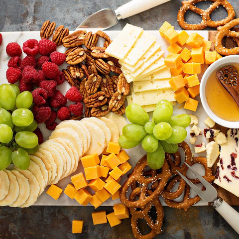 Snack platter with cheese, fruits, nuts, and mini pretzels