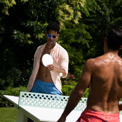 Guys playing ping pong together on the lawn