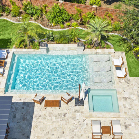 An aerial view of a luxurious backyard area, adorned with high quality outdoor furniture and in-pool chaises.