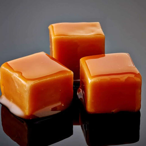 Three caramel cubes reflected on black surface