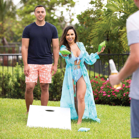 Friends playing cornhole on the lawn