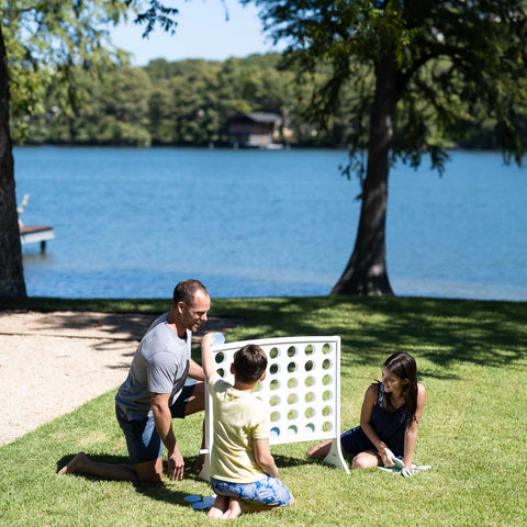 Family playing Four in a Row on the lawn