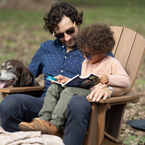 Father and son sitting and reading on an Adirondack chair