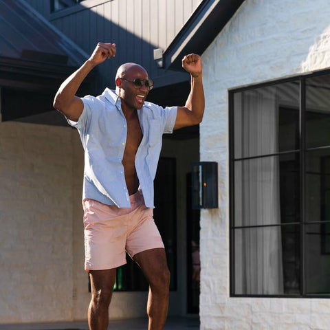 Man in bathing suit and open button down shirt cheering