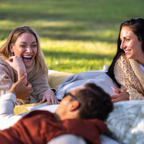 Friends relaxing on Laze Pillows out on the lawn