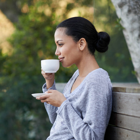 Woman sitting outside, sipping a warm drink