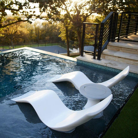 Two white Ledge Loungers Autograph Chaises with a side table between them, on a pool ledge