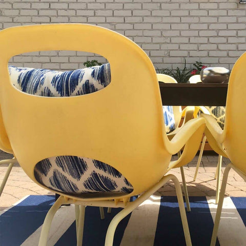 Back of yellow plastic chairs with cutouts that reveal throw pillows