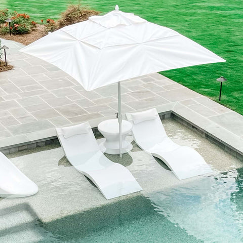 Pool ledge furniture with two in-pool chaise loungers, in-pool side table, and umbrella