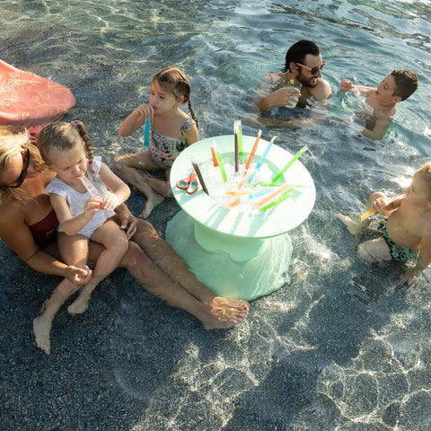 Children and adults eat ice pops in pool, surrounding Ledge Loungers in-pool ice bin filled with ice and ice pops
