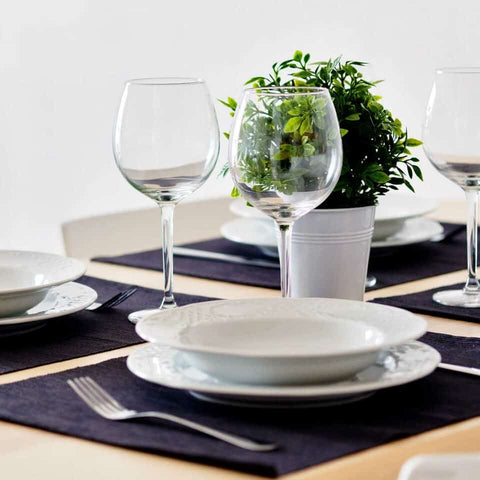 Basic table setting with essentials, white plates, wine glass and utensils