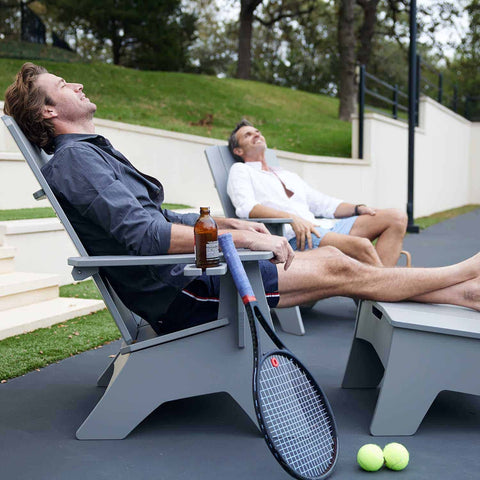 Men taking a break from playing tennis and relaxing on adirondack chairs