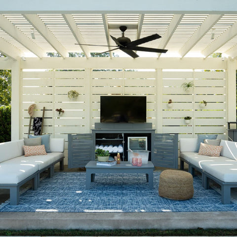 Two ottomans, a coffee table, and TV console credenza under a backyard pergola