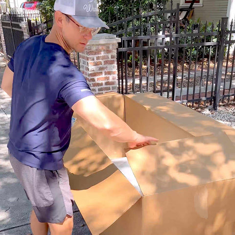 A homeowner unpacking a Ledge Lounger Signature Chaise from its packaging.