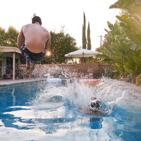 Friends having a cannoball competition in the pool