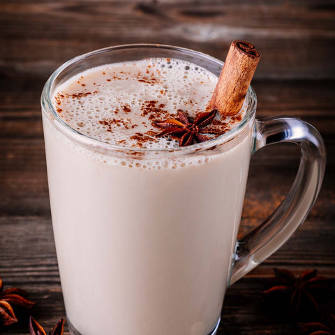 Chai tea latte in a clear glass mug with cinnamon and cloves