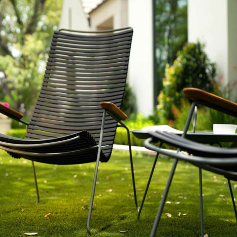 Two black metal chairs with brown arms on grass