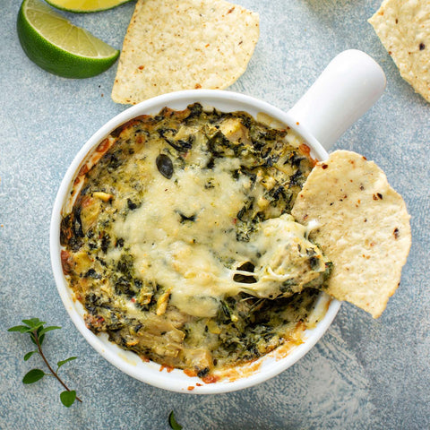 Chip dipped into a bowl of gooey spinach and artichoke dip