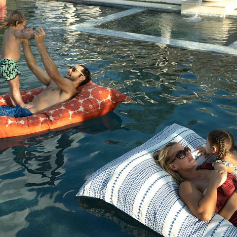 Two Ledge Lounger Laze pillows in a pool, each with a child and adult on them