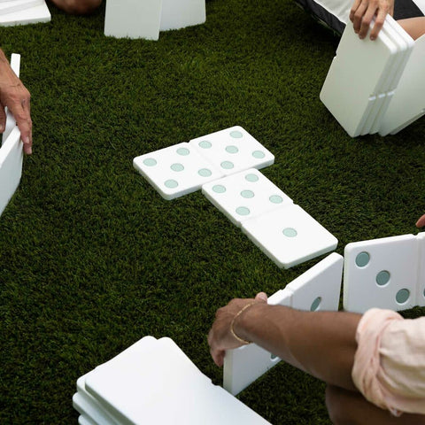 Hands playing with dominoes on grass