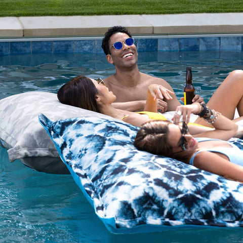 Friends relaxing and having fun on Laze Pillows in the pool