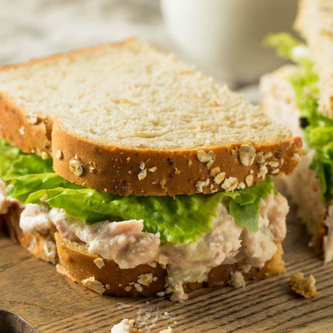 Closeup of half of a tuna fish sandwich with lettuce on whole wheat bread
