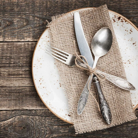 Vintage farmhouse table setting with burlap napkin on natural wood table