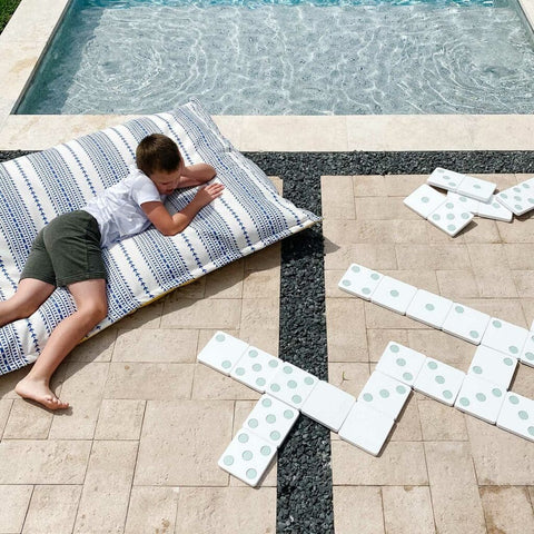 A boy relaxing by the backyard pool on a Ledge Lounger Laze Pillow