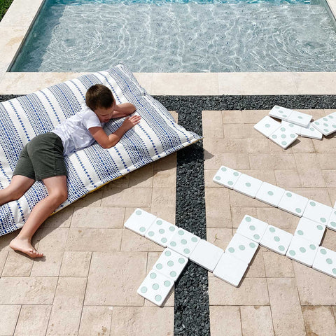 Kid on Laze Pillow by the pool, playing outdoor dominoes