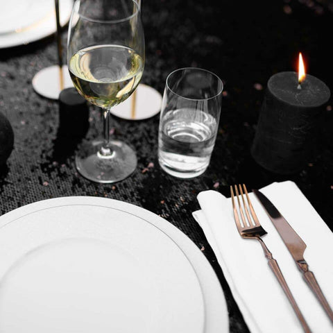 Simple, modern table setting with white place, wine glass and tableware