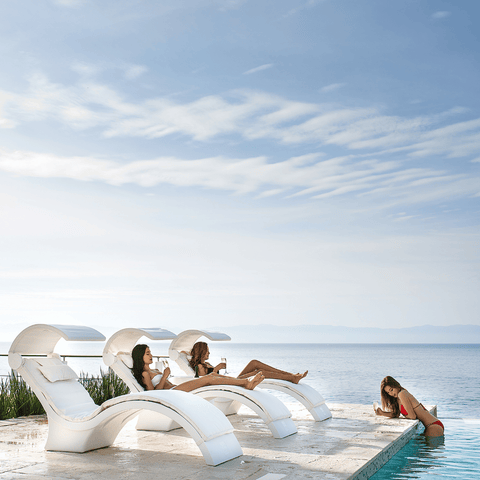 Women relaxing on Signature Chaise Deeps on the deck next to the pool