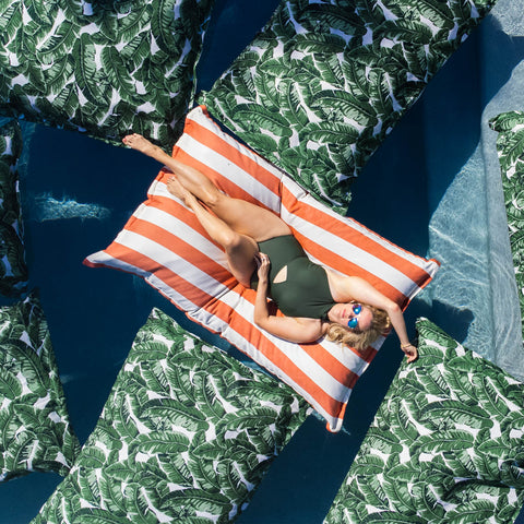 Woman floating on Laze Pillow in a pool surrounded by Laze Pillows