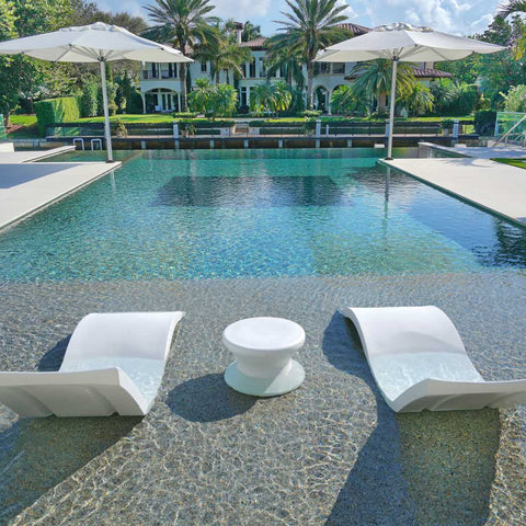 Pool with in-pool chaise loungers and side table on pool ledge