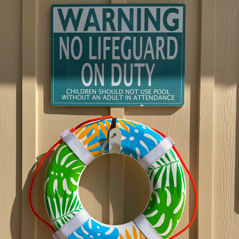 Lifesaver hanging on wall underneath a sign that reads "Warning: No Lifeguard on duty"